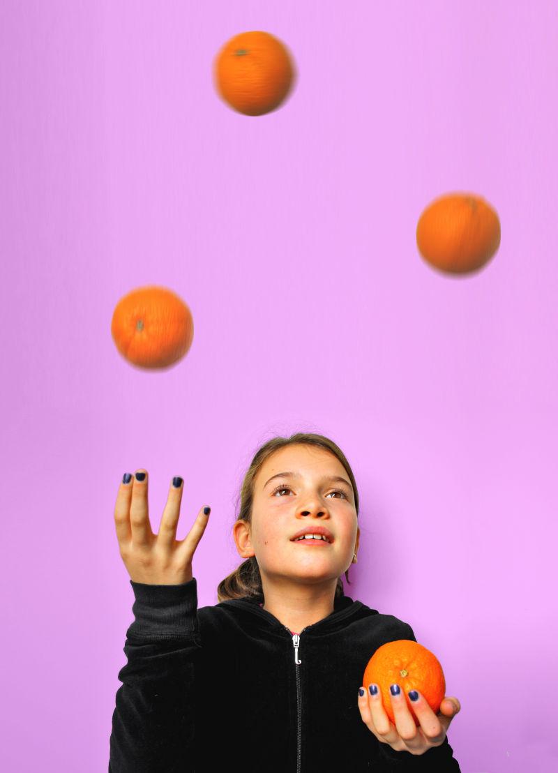 小女孩在玩橙子