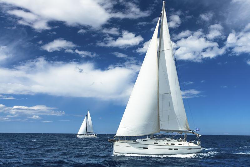 蓝天白云下白色的帆船行驶在蔚蓝的海面