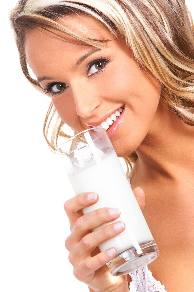 白色背景下年轻的美女在喝牛奶
