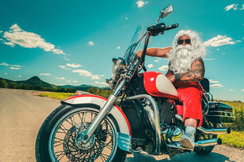 在蓝天白云下骑着摩托车的圣诞老人