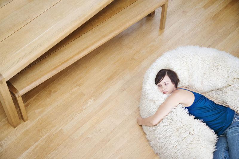 躺在木质地板的毛毯上的年轻女人
