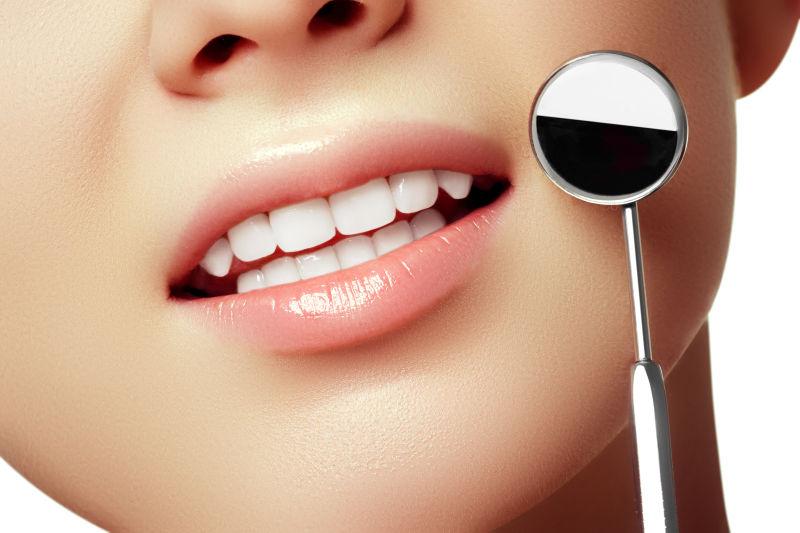 牙科医生的口镜检查女性牙齿