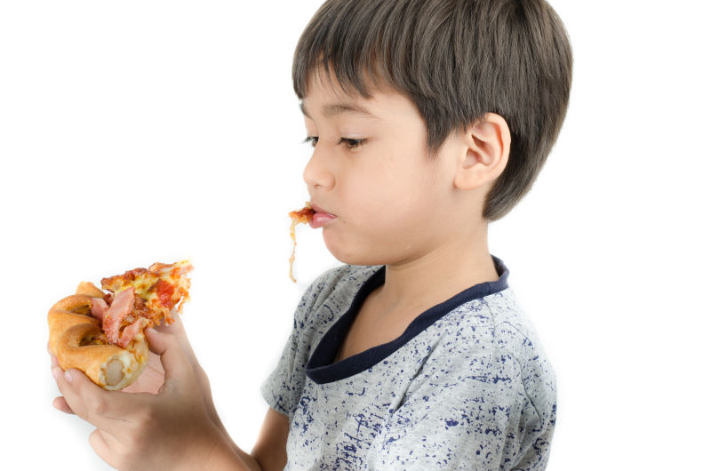 白色背景下吃比萨饼的小男孩