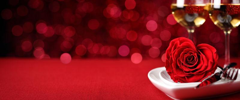 红色餐桌上的香槟酒杯和红色玫瑰花