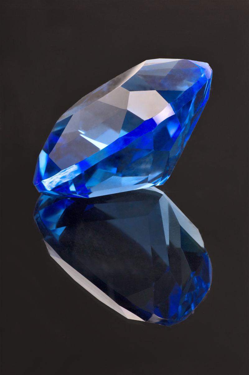 黑色背景下海蓝色宝石和桌面反射的形状