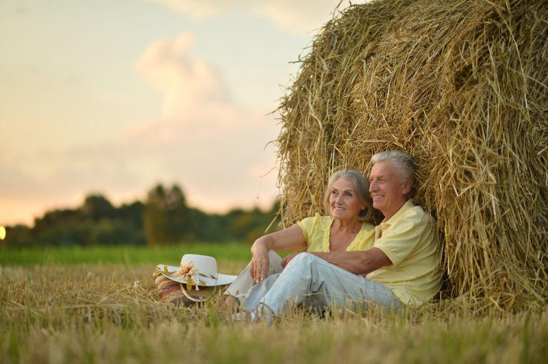 夕阳下靠在草垛上的恩爱老年夫妻