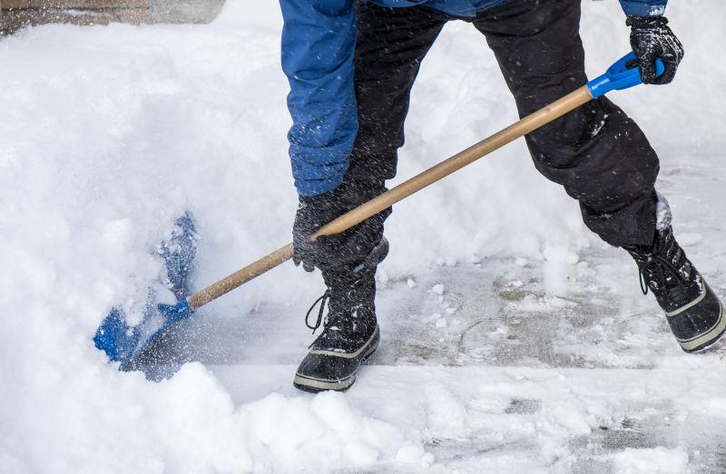 雪后男子用铁铲清除积雪