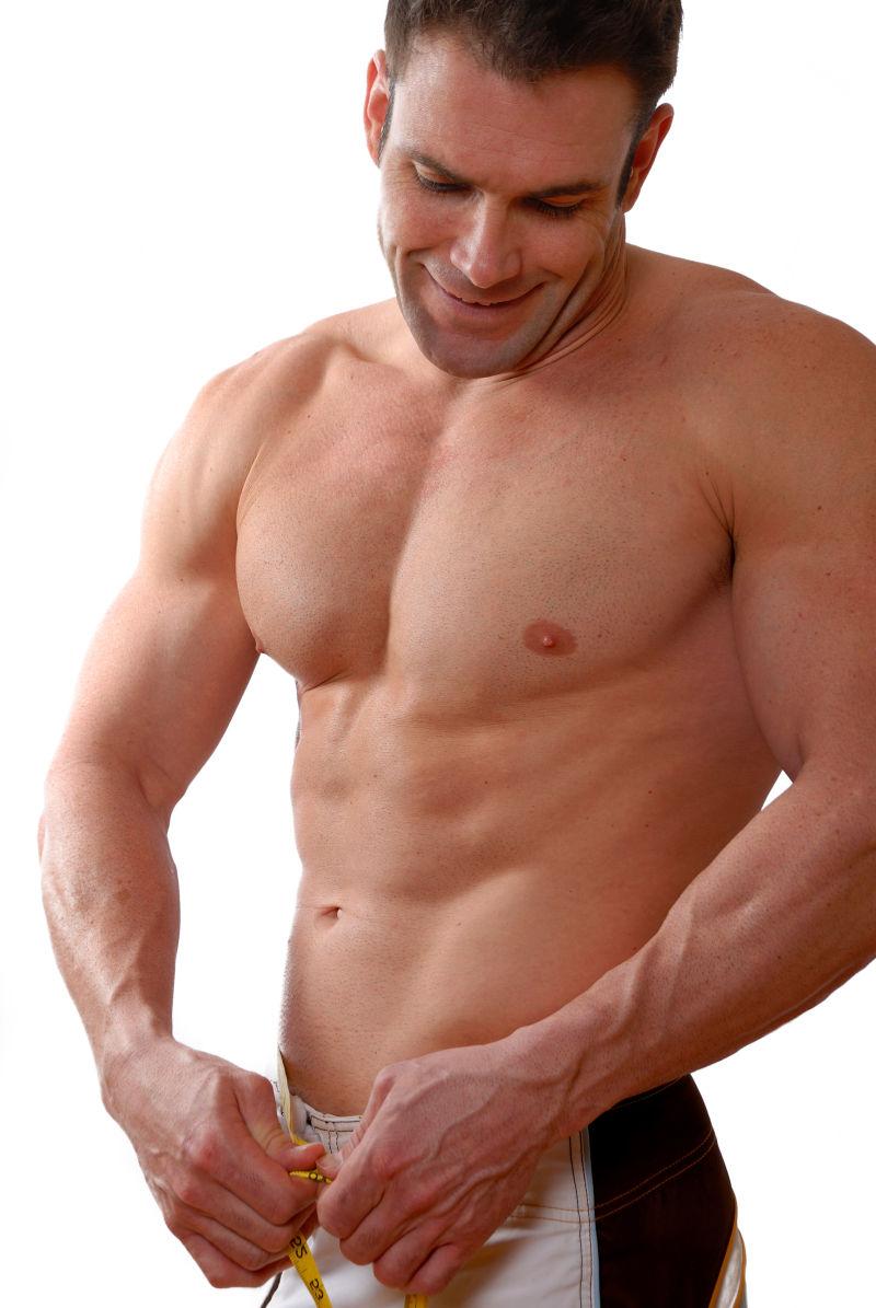 正在测量腰围的肌肉发达的男人