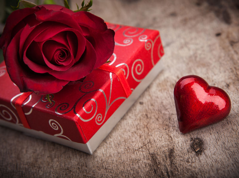 木板的情人节礼物盒上放着一朵美丽的红玫瑰