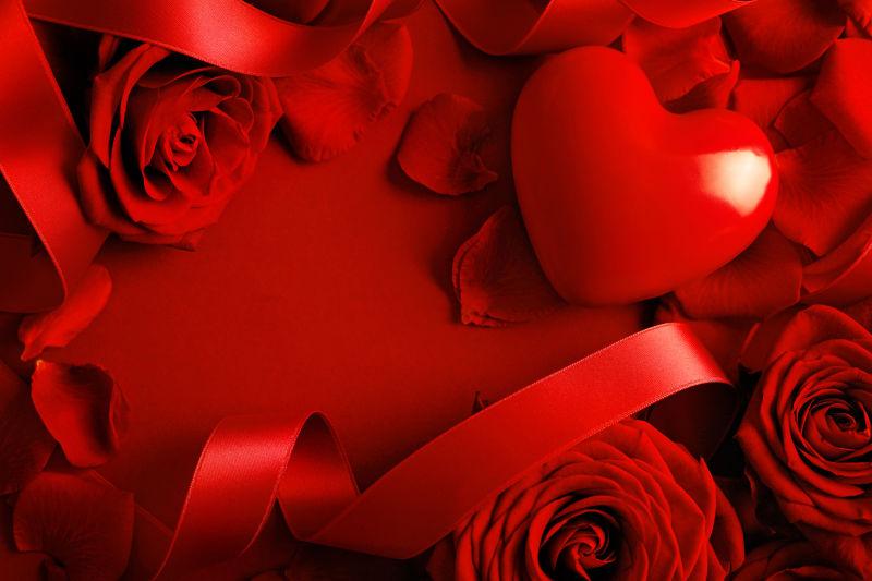 红色绸缎上的红色爱心和红色玫瑰花