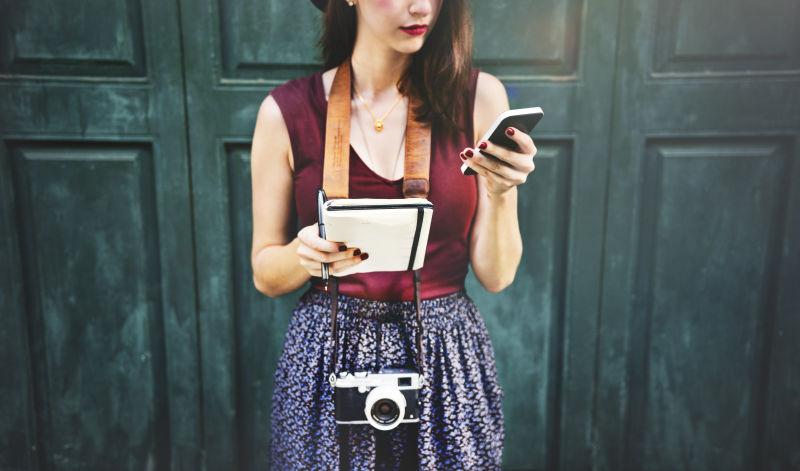 美女摄影师拿着笔记本和手机