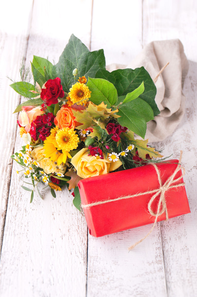 木板上的美丽花束和红色礼盒