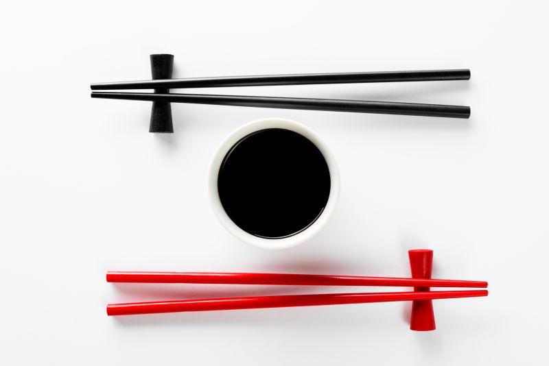 白色桌面上的酱油碗和红黑色筷子