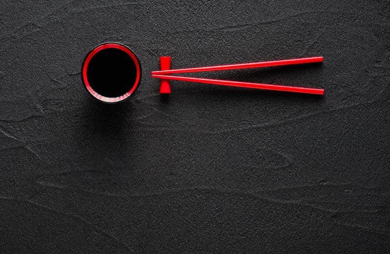 黑色桌面上的酱油碗和红色筷子