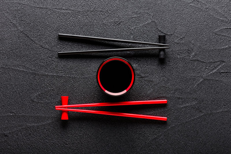 黑色桌面上的两双筷子和酱油碗