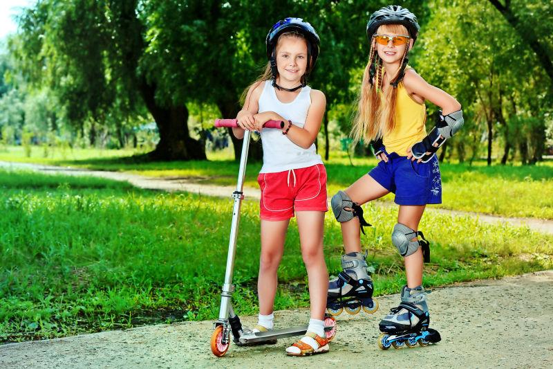 夏日公园里玩滚轴和滑板车的快乐女孩们