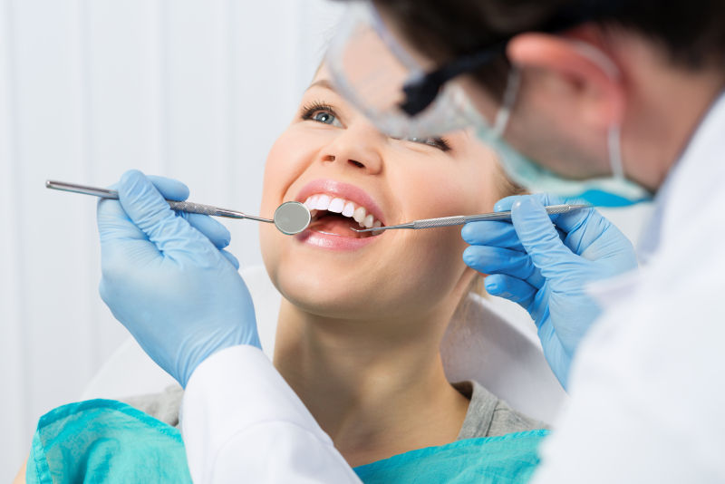 牙医为年轻妇女检查牙齿