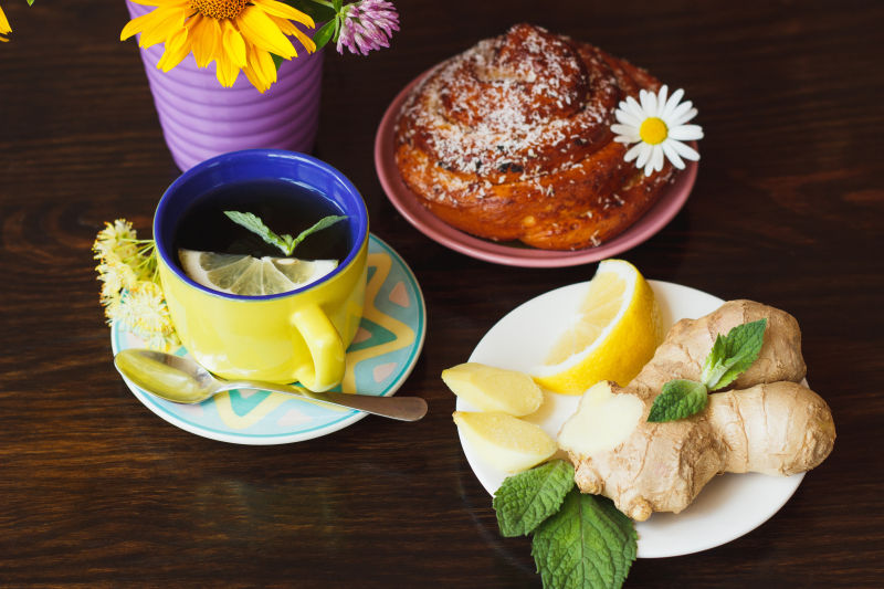 木制桌上的柠檬杯薄荷叶生姜和面包