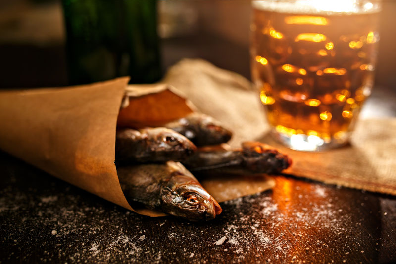 桌上装在纸袋里的干鱼和装在杯子里的啤酒