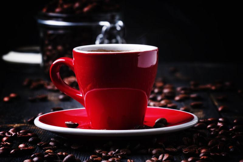 放满咖啡豆的桌面上有一杯红色的咖啡杯