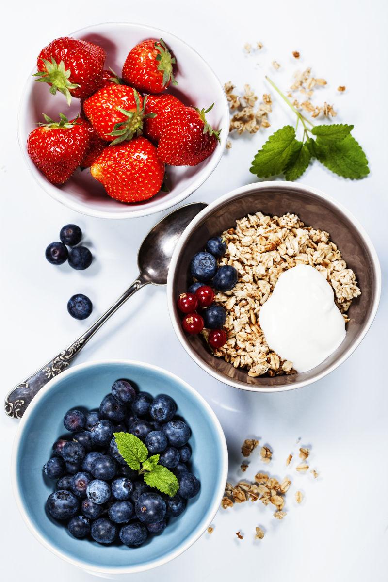 白色桌上有蓝莓草莓浆果和燕麦片的健康早餐