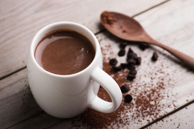 木制桌面中的热巧克力可可粉和汤匙