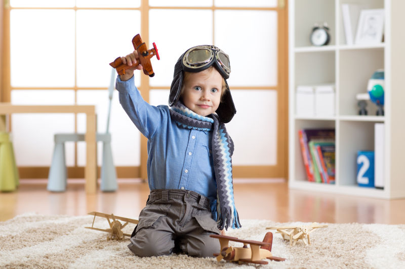 一身飞行员打扮的小男孩玩着木质飞机