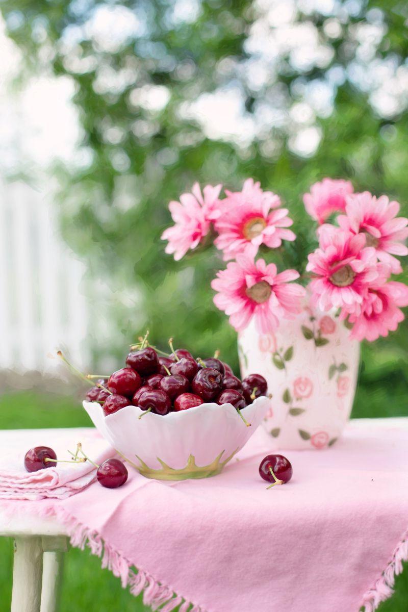 桌子上的粉色花朵和樱桃