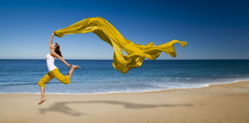 在沙滩上挥舞着黄色丝带的美女