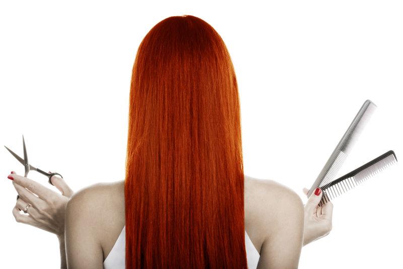白色背景下手拿理发工具的红发美女