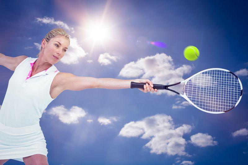 阳光蓝天下打网球的女运动员