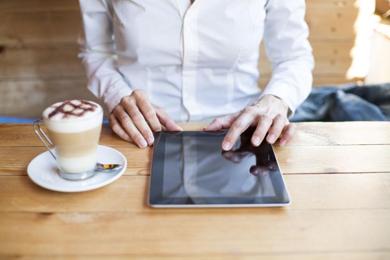 坐在咖啡馆使用平板电脑的商人