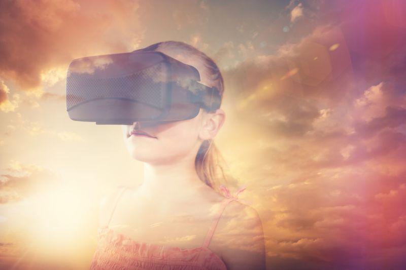 在日出背景下带着VR眼镜处于虚拟世界的女孩子