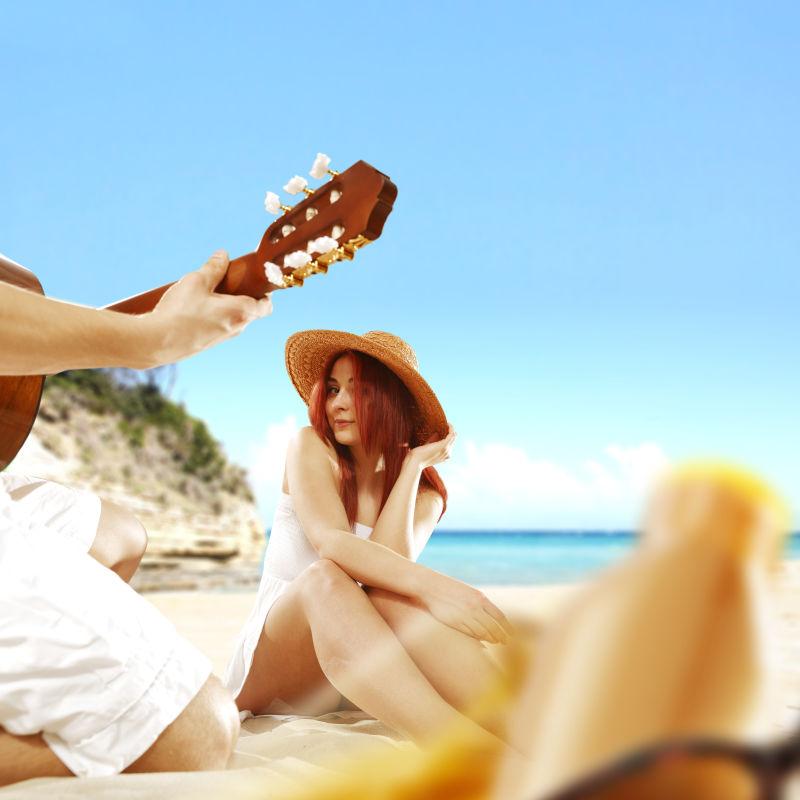沙滩上给女朋友弹奏吉他的男人