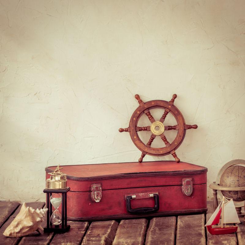 红色旅行皮箱上的木质船舵