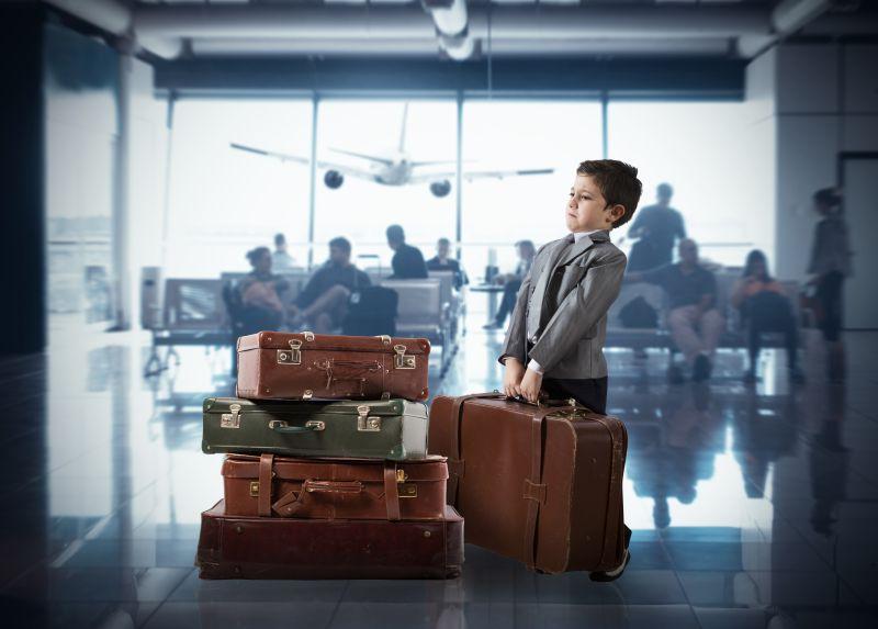 机场候机室里扛着行李箱的西装男孩