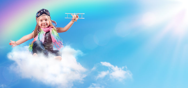 阳光下拿着小飞机坐在云朵上的小女孩