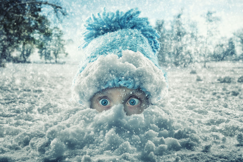 藏在雪地上露出眼睛的孩子