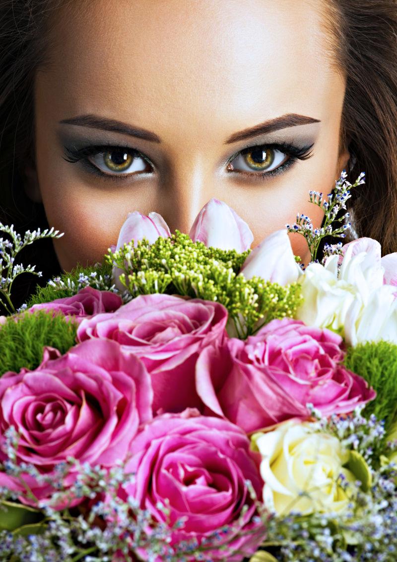 美丽的女孩用鲜花贴近自己的脸