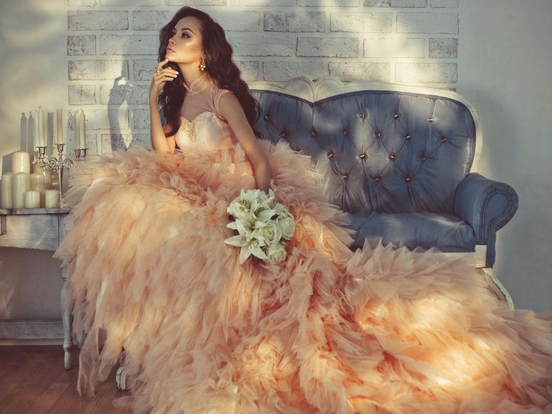 坐在沙发上穿着粉色华丽的礼服的漂亮女士