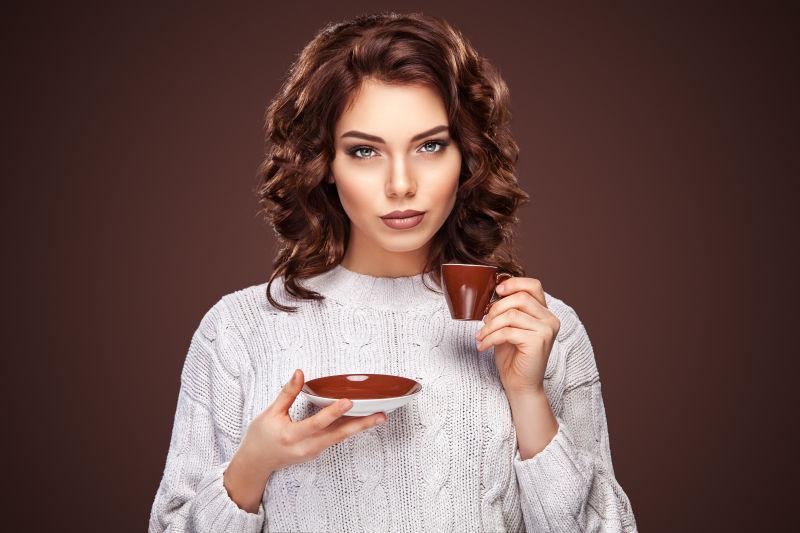 棕色背景上卷发美女拿着咖啡杯