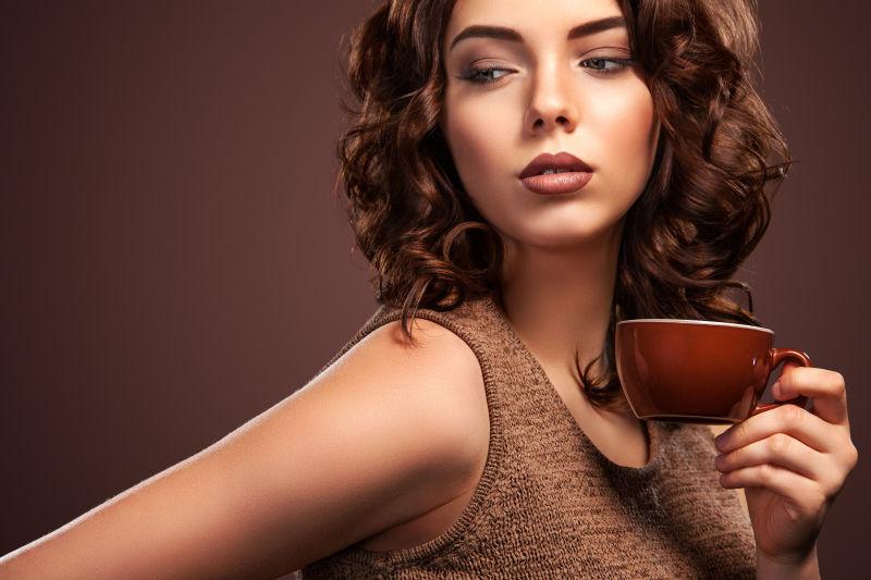棕色背景上优雅的卷发美女拿着咖啡杯