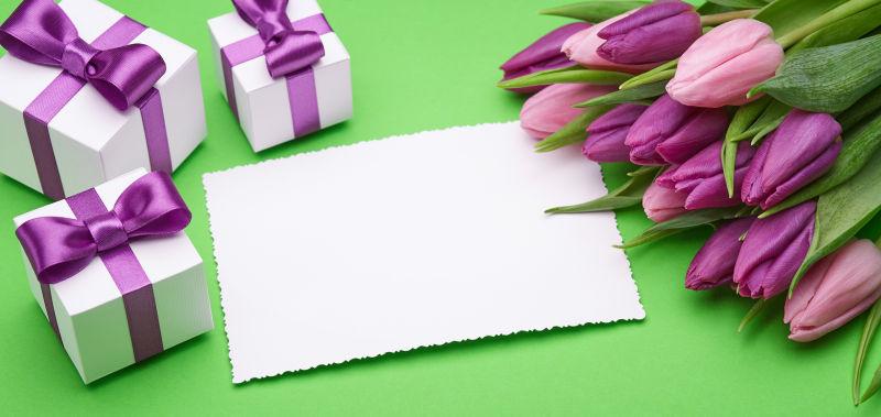 绿色背景中的卡片绸缎蝴蝶结装饰的礼盒和鲜花
