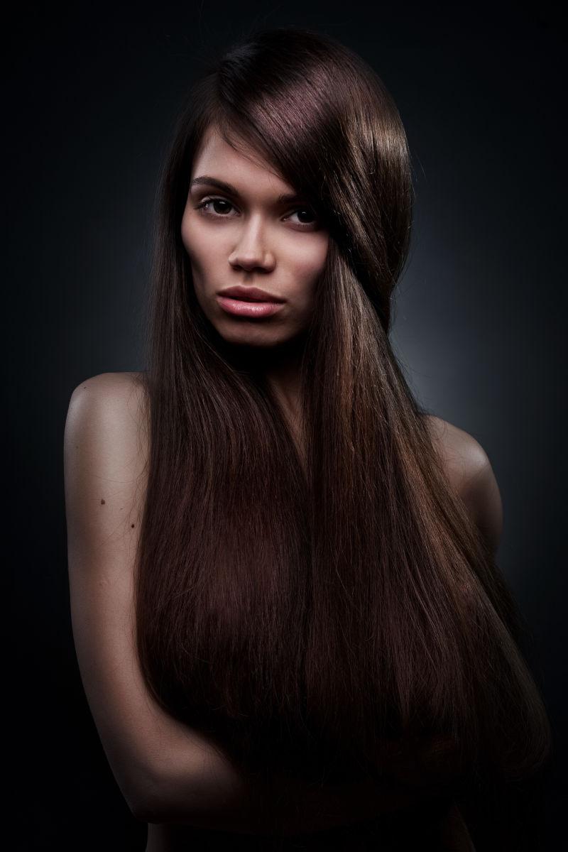 黑色背景下年轻迷人的长头发的女人肖像