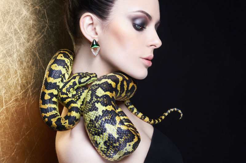 漂亮的年轻女子脖子上围着一条蛇