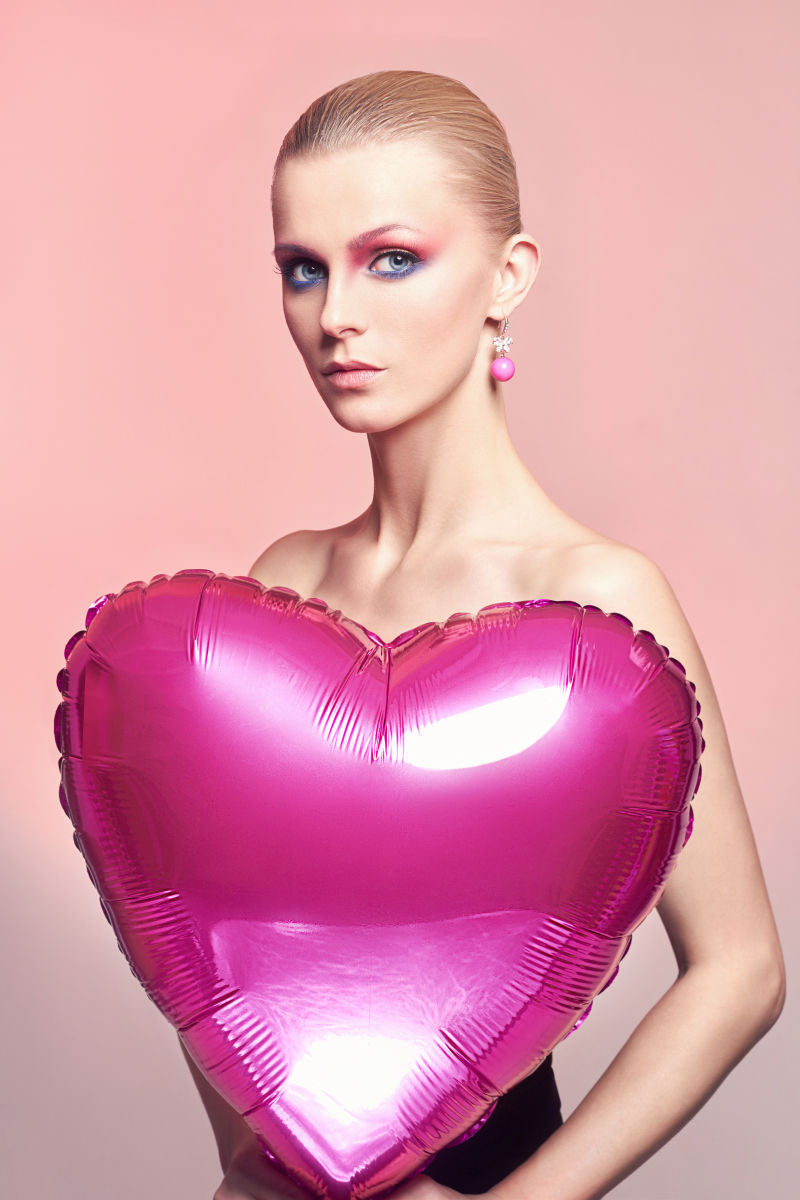 化妆的美女拿着粉色的爱心气球