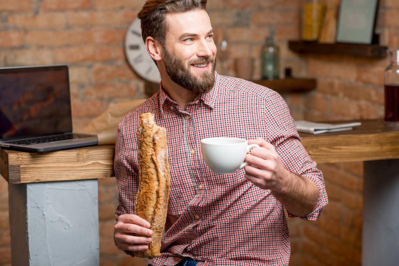 英俊男子在厨房吃咖啡和面包