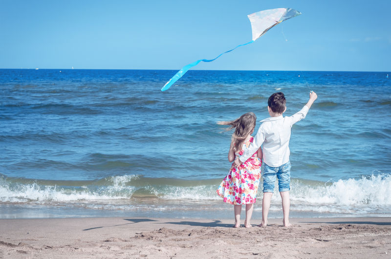 在海滩上放风筝的男孩和女孩