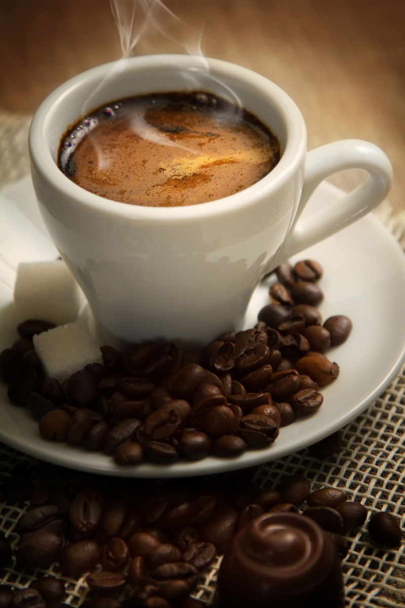 咖啡豆棕色背景的小杯黑咖啡