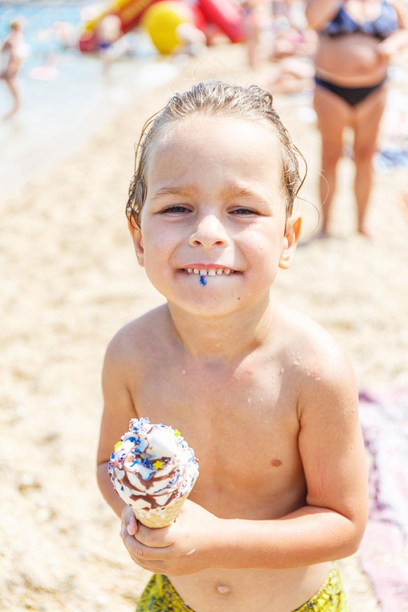 沙滩上开心吃冰淇淋的男孩